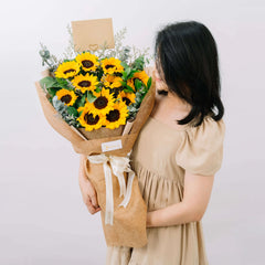 Woman holding bouquet of sunflowers and greenery for flower delivery