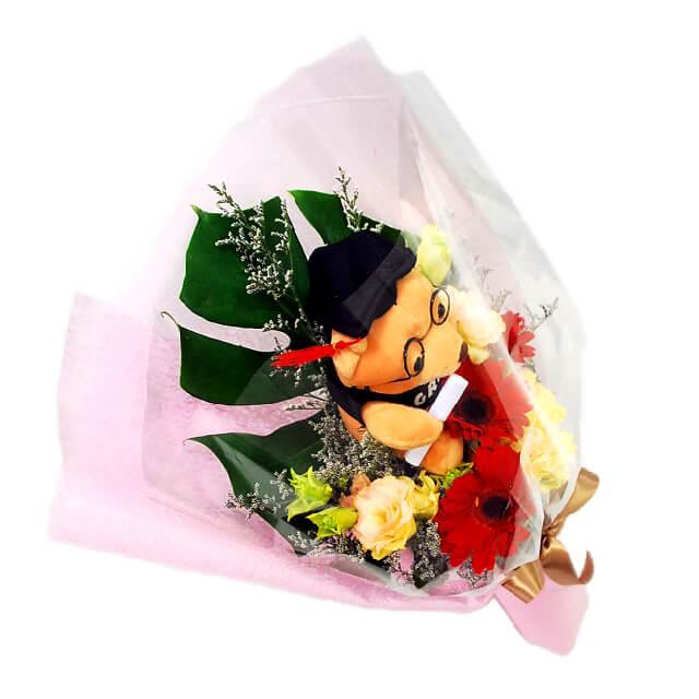 Graduation gift bouquet with red gerberas, rose flowers and a graduation bear for flower delivery