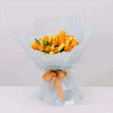 Bouquet of yellow and orange tulips wrapped for flower delivery