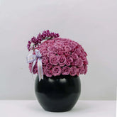 Elegant bouquet of pink roses and mini orchids in black vase for flower delivery