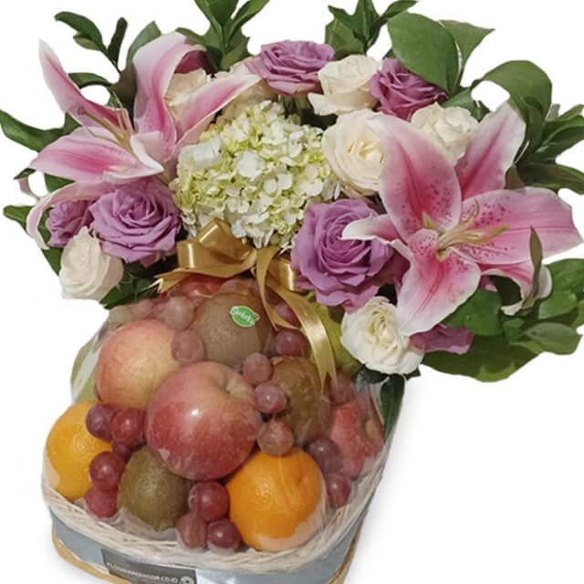 Elegant flower and fruit basket with lilies, roses, and assorted fresh fruits for delivery