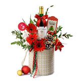 Festive flower delivery gift basket with wine, red flowers, pinecones, and Christmas decor