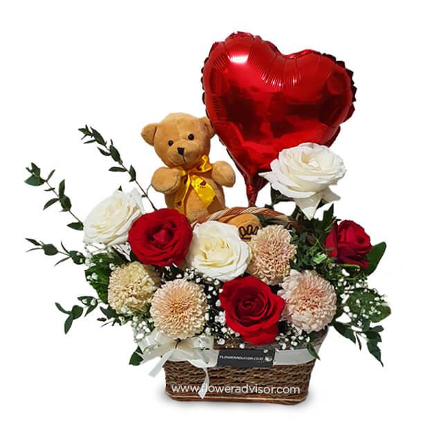 Flower delivery basket with red and white roses, teddy bear, and heart balloon