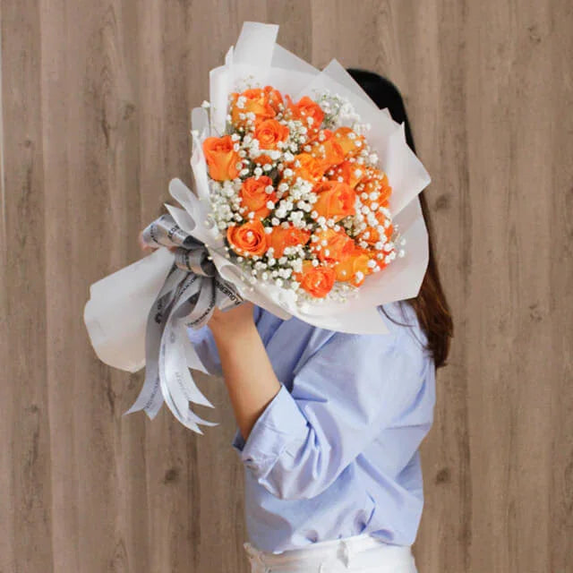 Woman presenting vibrant orange rose bouquet for flower delivery in Singapore