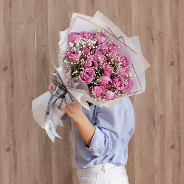 Hand holding purple rose bouquet with baby's breath, perfect for flower delivery in Singapore