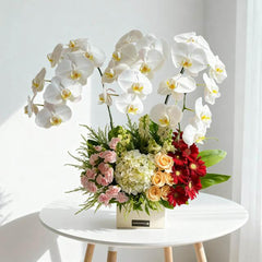 Elegant table flower arrangement with white orchids and mixed blooms for flower delivery