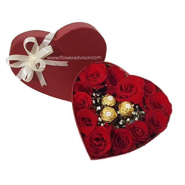 Heart-shaped flower box with fresh red roses and chocolates for romantic flower delivery