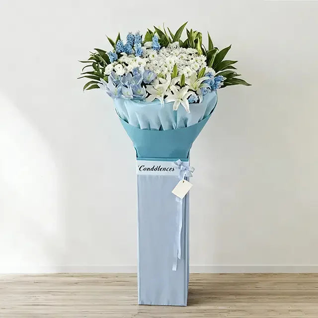 Blue and white condolence flower stand with lilies and roses for delivery