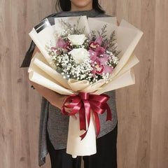 Elegant flower bouquet with white roses, pink orchids, red ribbon for delivery