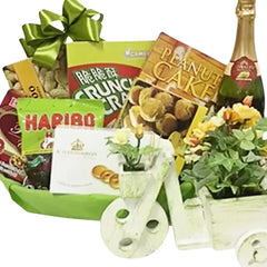 Flower delivery hamper with fresh flowers, snacks, and treats in a decorative basket