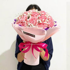 Hand holding pink carnation bouquet with baby's breath, ideal for flower delivery in Singapore