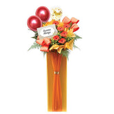 Grand opening flower stand with bright orange gerberas, balloons, and congratulatory card, ideal for flower delivery in Singapore.