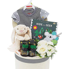 Newborn gift hamper with white roses, soft toy, baby clothes, and book for flower delivery