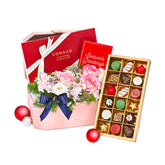 Festive flower arrangement with pink roses and seasonal chocolates, perfect for flower delivery gift