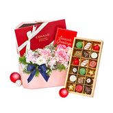 Festive flower arrangement with pink roses and seasonal chocolates, perfect for flower delivery gift