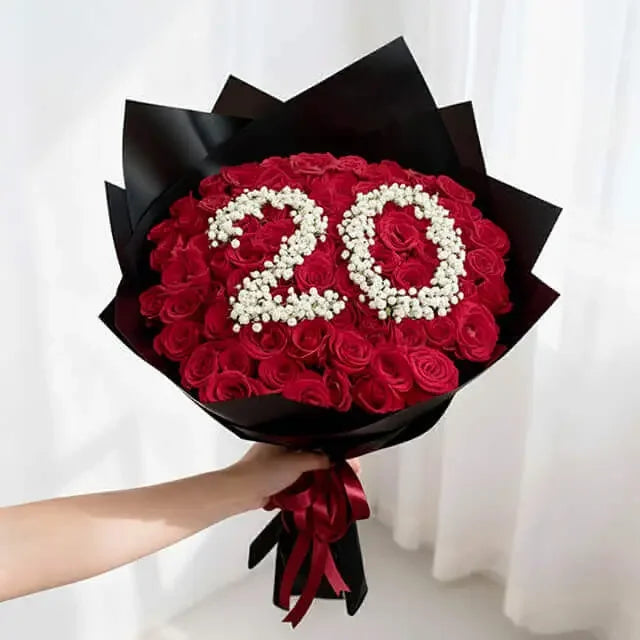 Hand holding a bouquet of red roses with '20' in white flowers for flower delivery