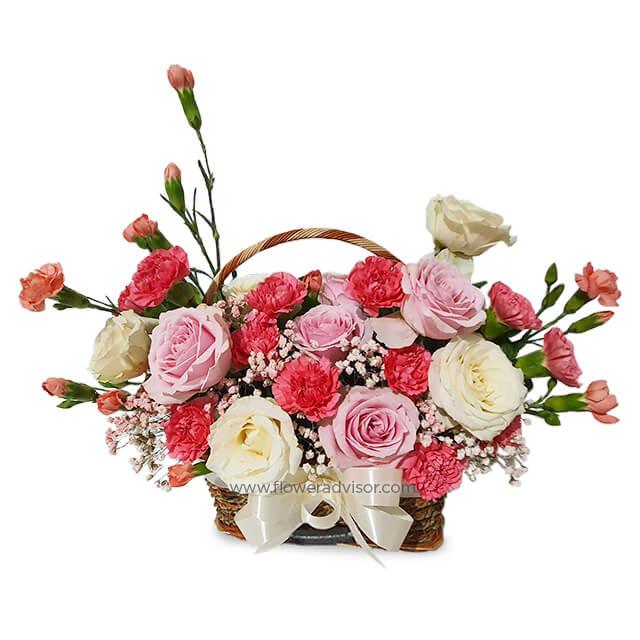 Pink and white roses and carnations in a basket, perfect for flower delivery in Singapore