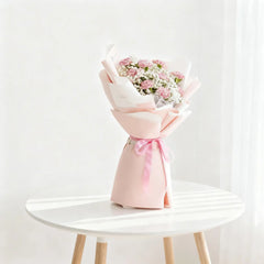 Pink and white flower bouquet for delivery, wrapped with ribbon on round table