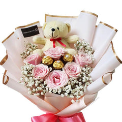 Elegant flower delivery bouquet with pink roses, baby’s breath, chocolates, and teddy bear.