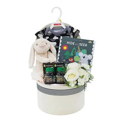 Flower delivery gift hamper with white roses, baby clothes, plush toy, and children's book