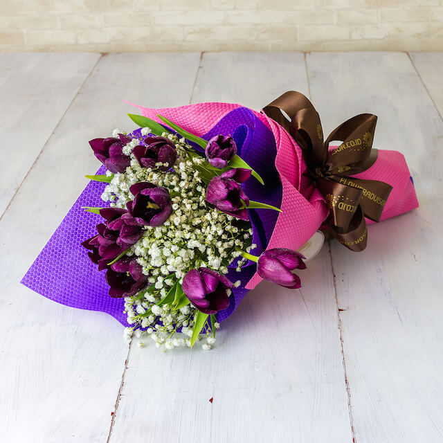 Purple tulip bouquet with baby's breath for flower delivery, wrapped in pink and purple.