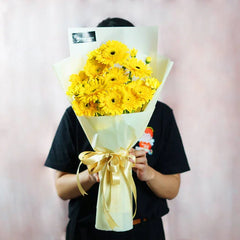 Hand holding a bouquet of fresh yellow gerbera daisies for flower delivery