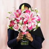 Hand holding pink lilies and roses bouquet in vase for flower delivery