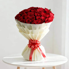 Bouquet of red roses in white wrapping with red ribbon for flower delivery