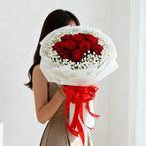 Woman holding elegant red rose bouquet with white flowers for flower delivery