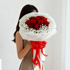 Woman holding elegant red rose bouquet with white flowers for flower delivery