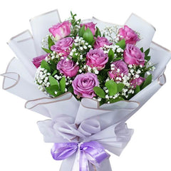 Purple rose bouquet with baby's breath and greenery, wrapped in white paper for flower delivery