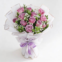 Elegant purple rose bouquet with white baby's breath, wrapped for flower delivery.
