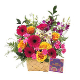 Colorful flower arrangement with roses, gerberas, orchids, and a decorative bow in a basket, ideal for flower delivery