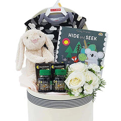 Flower delivery gift hamper with white roses, plush bunny, baby outfit, supplements, and book