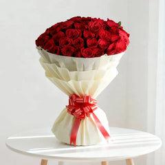 Elegant bouquet of red roses with white wrapping and red ribbon, ideal for flower delivery