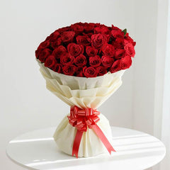 Luxurious bouquet of red roses with white wrapping and red ribbon, perfect for flower delivery