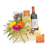 Festive flower delivery hamper with fresh flowers, wine, chocolate, nuts, fruits, and greeting card