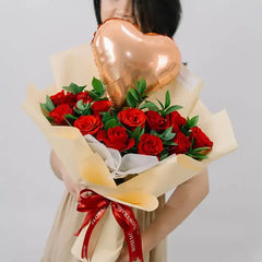 Bouquet of red roses with ruscus leaves and heart balloon for flower delivery