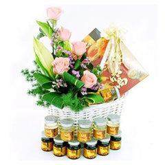 Flower delivery basket with pink roses, assorted greenery, and wellness gifts.