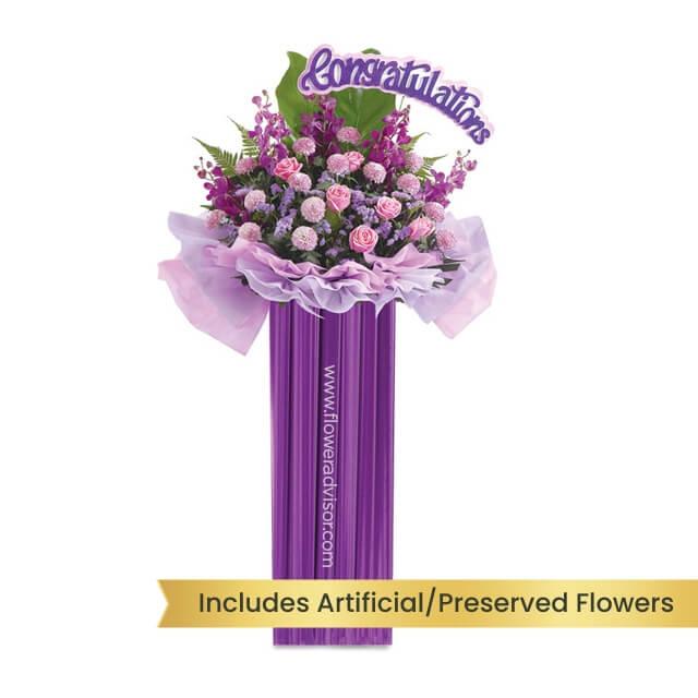 Purple flower stand with pink roses and congratulatory sign for flower delivery