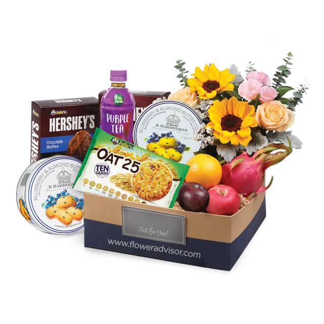 Flower delivery gift box with sunflowers, roses, fresh fruits, cookies, snacks, and tea