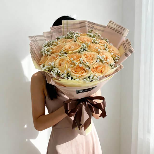 Peach rose bouquet with baby's breath for flower delivery, wrapped in pastel paper and ribbon