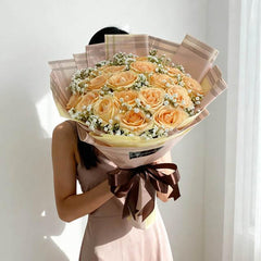 Peach rose bouquet with baby's breath for flower delivery, wrapped in pastel paper and ribbon