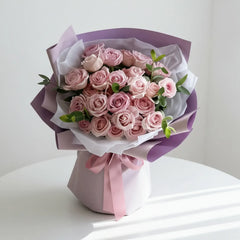Elegant pink rose bouquet with greenery for flower delivery, wrapped in purple paper and ribbon