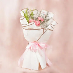 Pink carnation bouquet wrapped in white paper with pink ribbon, perfect for flower delivery