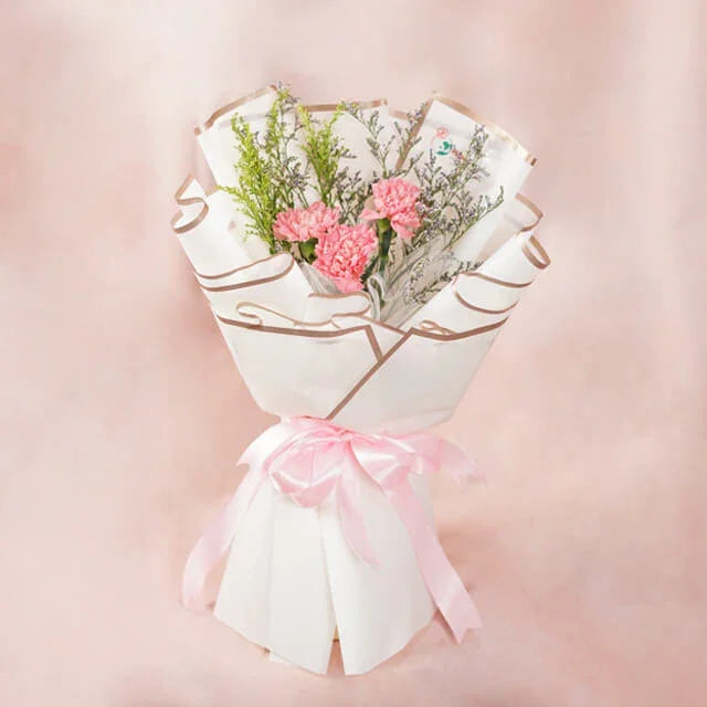 Pink carnation bouquet wrapped in white paper with pink ribbon, perfect for flower delivery