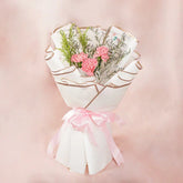 Pink carnation bouquet wrapped in white paper with pink ribbon, perfect for flower delivery