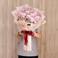 Hand holding large pink rose bouquet with baby's breath for flower delivery