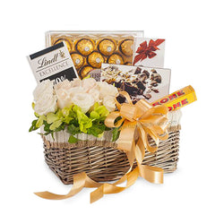 Flower delivery basket with white roses, greenery, chocolates and gold ribbon