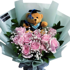 Graduation flower bouquet with pink roses, bear plush, and baby’s breath for flower delivery